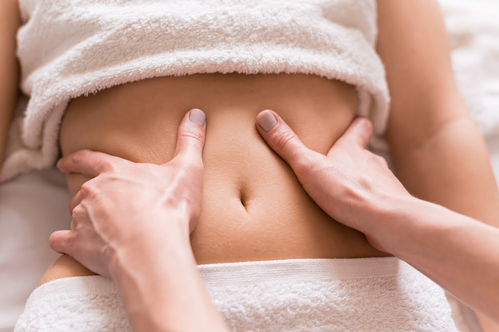 Plano fechado de barriga feminina recebendo drenagem linfática manual, representando os benefícios da drenagem linfática manual para redução de inchaço e retenção de líquidos.